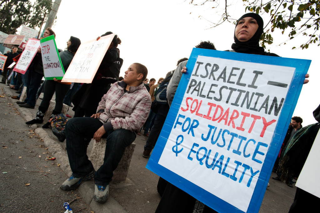 A Palestinian woman holds a sign reading "Israeli-Palestinian Solidarity for Justice & Equality" as Israeli, and international solidarity activists stage a weekly demonstration in the Sheikh Jarrah neighborhood of East Jerusalem to protest the takeover of Palestinian homes by Jewish Israeli settlers, December 10, 2010.